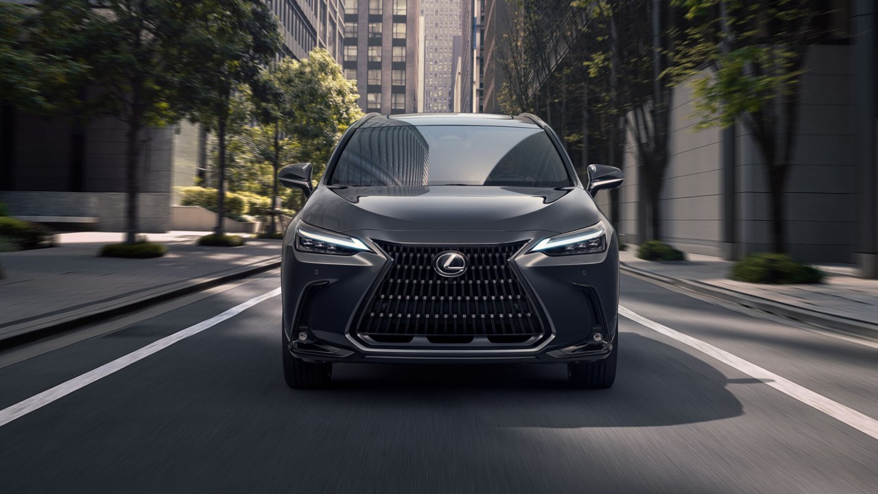 A Lexus NX 450h+ driving through a city location 