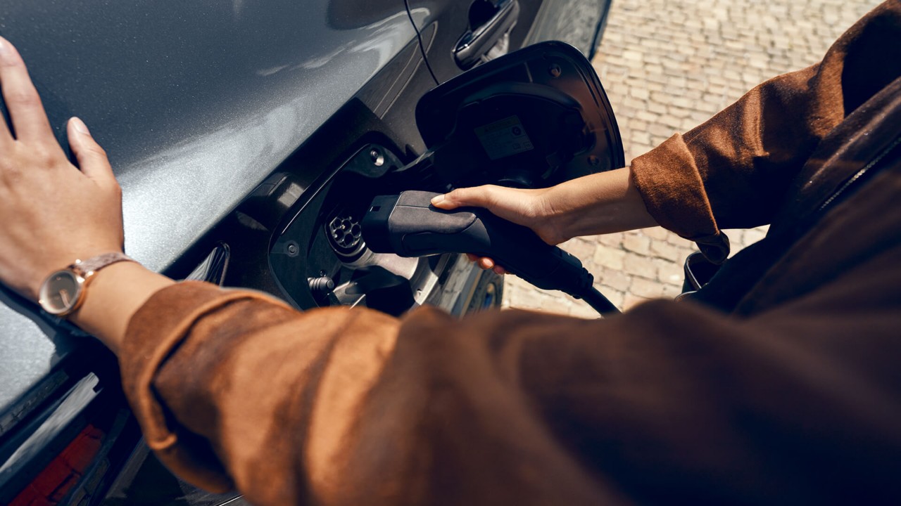 A person plugging in a charging socket into a Lexus 