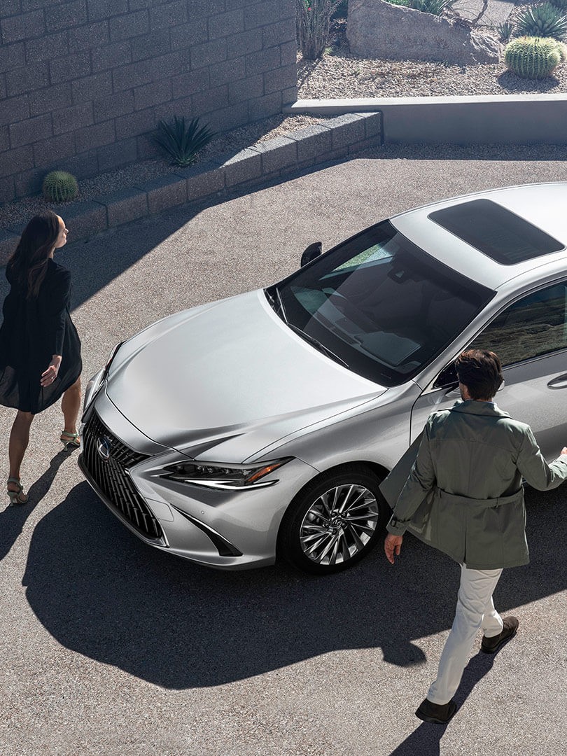 A man and woman wallking towards a Lexus ES 300h