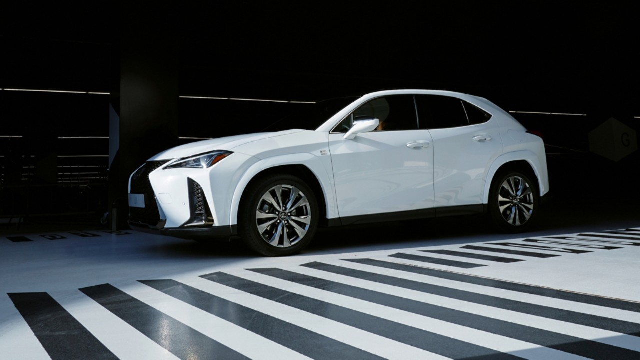 A white Lexus parked next to a black and white patterned floor